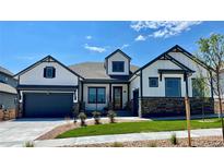 Beautiful exterior of this home featuring a two-car garage, stone accents, a well-manicured lawn, and a welcoming front porch at 18704 W 95Th Ln, Arvada, CO 80007