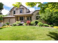 Charming two-story home with a stone facade, manicured lawn, and colorful flower beds at 2480 W Jamison Way, Littleton, CO 80120