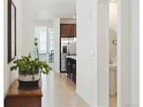 Hallway view showcasing wood floors, leading to the kitchen and a room with glass doors at 8844 S Sicily Ct, Aurora, CO 80016