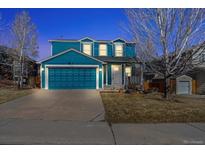 Charming two-story home with blue siding, attached garage, and well-maintained front yard at 8731 Wildrye Cir, Parker, CO 80134