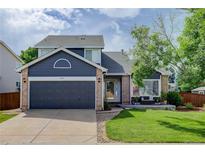 Charming two-story home with a well-maintained lawn, brick accents, and a dark blue garage door at 8915 Edgewood Ln, Highlands Ranch, CO 80130