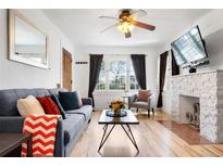 Bright living room with a gray sofa, a stone fireplace, and many windows at 3319 E 27Th Ave, Denver, CO 80205