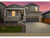 Charming two-story home with a covered porch, stone accents, and a two-car garage at sunset at 571 Homestead Ave, Brighton, CO 80601