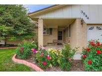 Inviting front porch with brick pillars and colorful rose bushes at 3544 Dyanna Dr, Thornton, CO 80241