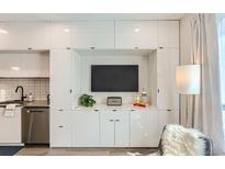 Modern living room boasts sleek white cabinetry with built-in entertainment center and stainless steel kitchen appliances at 2120 N Downing St # 216, Denver, CO 80205