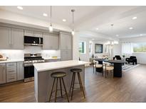 Modern kitchen with gray cabinets, stainless steel appliances, island, and dining area with hardwood flooring at 8408 W 52Nd Ave, Arvada, CO 80002
