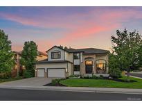 Stunning two-story home with a three-car garage, manicured lawn, and brick accents at sunset at 10701 Flagler Dr, Parker, CO 80134