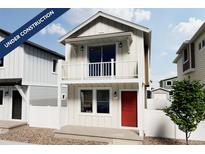 Charming two-story home showcasing a balcony, red front door, white picket fence and modern architectural details at 10379 Vaughn Way, Commerce City, CO 80022