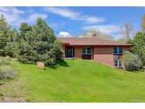 Charming brick home featuring a well-manicured lawn and mature tree providing shade and curb appeal at 6155 Meadowbrook Dr, Morrison, CO 80465