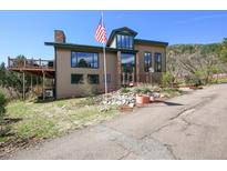 Inviting two-story home with a deck and lush landscaping. Front yard has american flag and stone features at 6584 Pike Cir, Larkspur, CO 80118