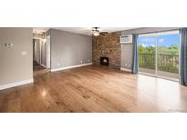 Bright living room features beautiful stone fireplace, hardwood floors, and sliding glass door to balcony at 381 S Ames St # F204, Lakewood, CO 80226