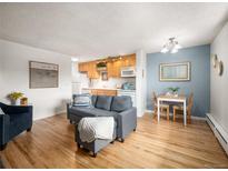 Bright living room featuring hardwood floors, a comfortable gray sofa and an adjacent dining space at 155 S Pennsylvania St # 310, Denver, CO 80209