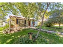 Charming home featuring a quaint front porch, lush lawn, and mature trees providing ample shade at 331 Sherman St, Longmont, CO 80501