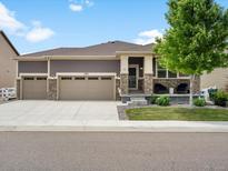 Inviting home with a three-car garage, stone accents, covered porch, and a well-manicured front yard at 5205 Periwinkle Way, Brighton, CO 80640