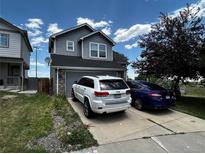 A two-story home with gray siding, a two car garage, and a concrete driveway on a sunny day at 2005 W 86Th Ave, Denver, CO 80260