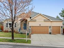 Charming single-Gathering home featuring a three-car garage, stone accents, and a manicured front yard at 5497 W Prentice Ct, Littleton, CO 80123