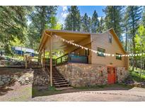 Charming home exterior features a stone foundation, covered patio, and views of the surrounding wooded landscape at 7364 Rossman Gulch Rd, Morrison, CO 80465