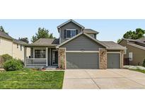 Charming home featuring a well-manicured lawn, covered porch, and two-car garage at 13472 Columbine Cir, Thornton, CO 80241
