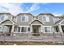 Charming townhome featuring a well-kept, green exterior with stone accents and a cozy front porch at 15945 E Geddes Dr # 54, Aurora, CO 80016