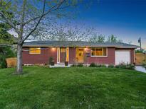 Charming brick home features a well-manicured lawn and inviting front entrance at dusk at 207 Iowa Dr, Golden, CO 80403