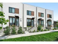 Modern townhome exterior with beautiful front yard landscaping and individual entryways with dark metal awnings and railings at 4394 Zenobia St, Denver, CO 80212