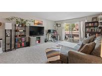 Inviting living room with balcony access, cozy gray couch, and a dedicated workspace at 7755 E Quincy Ave # 207A3, Denver, CO 80237