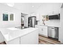 Bright kitchen features stainless steel appliances, white cabinets, and a modern cooktop island at 469 S Perry St, Denver, CO 80219