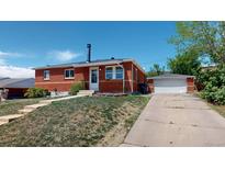 Charming red brick home with well-maintained lawn and detached garage on a sunny day at 2533 E 90Th Pl, Thornton, CO 80229