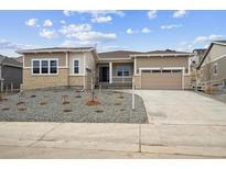 Tan home with a two-car garage, rock landscaping, and covered porch at 4723 Twelve Oaks Way, Castle Rock, CO 80104