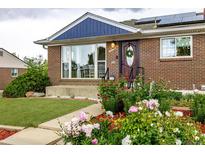 Charming brick home with solar panels and a beautiful flower-filled front yard and landscaped lawn at 10478 Ogden St, Northglenn, CO 80233