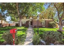 Charming two-story home with brick accents, a well-manicured lawn, and mature trees at 8150 S Marshall Ct, Littleton, CO 80128