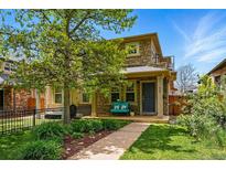 Charming stone-clad two-story home with landscaped front yard and inviting blue bench on the front porch at 557 S Clarkson St, Denver, CO 80209
