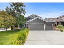 Charming two-story home features a three-car garage, lush lawn, mature tree, and meticulously maintained landscaping at 6772 Tiger Tooth, Littleton, CO 80124