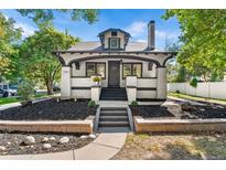 Charming home with a white painted brick exterior, black trim, landscaped front yard, and inviting front porch at 7204 W 26Th Ave, Lakewood, CO 80214