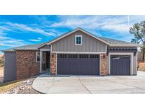 Two-story home with gray siding, stone accents, and a three-car garage at 8695 Thunderbird Cir, Parker, CO 80134