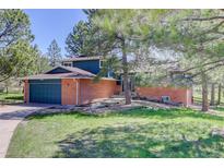 Charming home with a brick exterior, blue siding, mature trees and a well-manicured lawn at 7420 Windwood Way, Parker, CO 80134