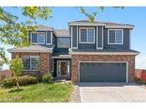 Charming two-story home featuring a brick facade, gray siding, and attached two-car garage, plus a well-manicured lawn at 2509 S Bahama Way, Aurora, CO 80013