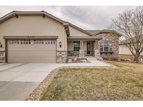 Charming home exterior with stone accents, a two-car garage, and a well-manicured lawn at 16399 Somerset Dr, Broomfield, CO 80023