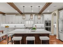 Spacious kitchen featuring a large island, stainless steel appliances, and white cabinetry with wooden accents at 9797 Sunset Hill Cir, Lone Tree, CO 80124