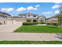 Charming two-story home featuring a three car garage, manicured lawn, and lush landscaping at 6566 S Telluride St, Aurora, CO 80016
