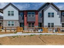 Modern townhomes feature a stone and vinyl facade and a quaint fenced yard at 2877 E 103Rd Dr, Thornton, CO 80229