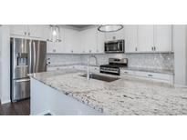 Bright kitchen features stainless steel appliances, white cabinets, and a large granite island with a sink at 18189 House Finch Ln, Parker, CO 80134
