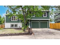 Two-story home featuring an attached garage, lush trees, and well-maintained landscaping at 10718 Ash Ct, Thornton, CO 80233