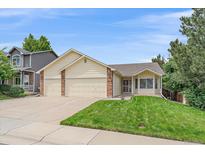 Inviting home featuring an attached two-car garage, well-maintained lawn, and charming curb appeal at 12229 W Berry Ave, Littleton, CO 80127
