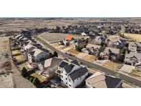 A neighborhood with a green space including two cars parked in front of the house with a mountain view in the background at 15753 E Indian Brook Cir, Parker, CO 80134