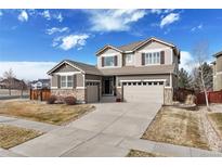 Charming two-story home featuring stone accents, a well-manicured lawn, and a three-car garage at 15753 E Indian Brook Cir, Parker, CO 80134