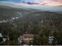 Scenic aerial view of a home nestled among lush evergreen trees with mountains in the background at 28254 Tresine Dr, Evergreen, CO 80439
