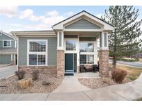 Charming home with green siding, stone accents, and large windows providing ample natural light at 13706 Legend Trail # 104, Broomfield, CO 80023