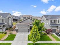 Charming gray home with a well-manicured lawn and lovely landscaping creating wonderful curb appeal at 18036 E 99Th Ave, Commerce City, CO 80022