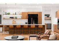 Modern kitchen features island with seating, black refrigerator, white countertops and open shelving at 1 S Forest St, Denver, CO 80246
